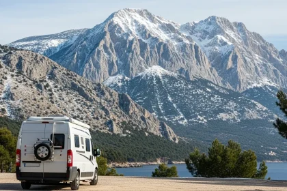 Van blanc garé face au mont Olympe enneigé